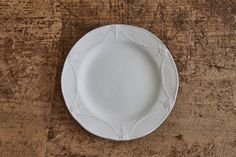 an empty white plate sitting on top of a wooden table next to a knife and fork