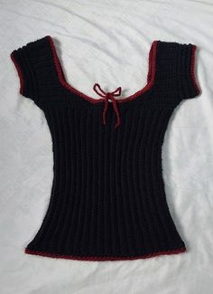 a black and red sweater laying on top of a bed