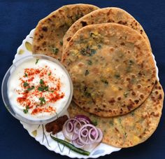 three pita breads on a plate with onion and yogurt