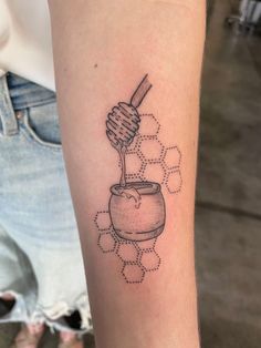 a tattoo with a honeycomb and a jar on it's arm that is filled with honey