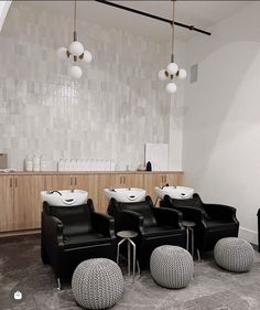 three chairs and two stools in a room with lights hanging from the ceiling above them