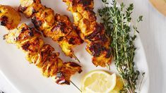 chicken skewers on a plate with lemon wedges