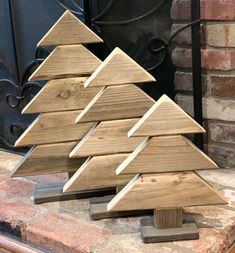 a small wooden christmas tree sitting in front of a fireplace