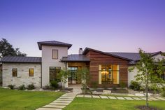 a modern home with stone walkway leading to the front door and entry way at dusk