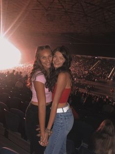 two young women standing next to each other in front of an audience at a concert