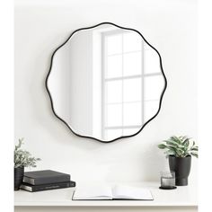 a mirror that is sitting on top of a shelf next to a book and potted plant