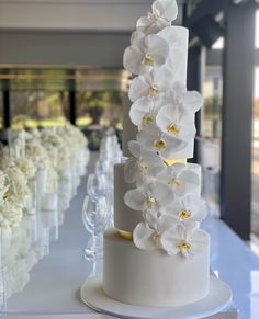 there is a white cake with flowers on the top and bottom, along with wine glasses