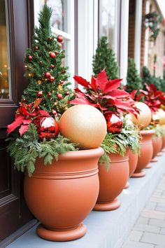 christmas decorations are lined up in clay pots on the side of a building with red and green poinsettis