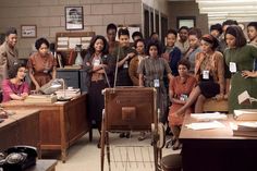 a group of people standing in an office with desks and telephones on the floor