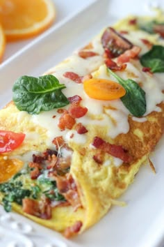 an omelet with bacon, spinach and tomatoes on a white platter