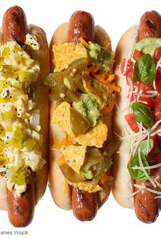 three hot dogs with toppings on them sitting next to each other