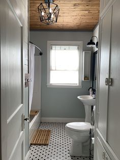 a white toilet sitting in a bathroom next to a sink under a window with a wooden ceiling