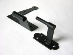 two black metal brackets on a white surface with one holding the other's handle