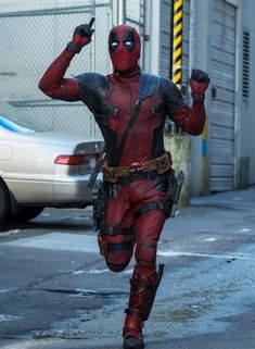 deadpool running on the street with his hands in the air