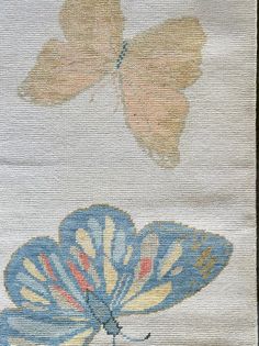 two butterflies on white fabric with blue and yellow colors, one flying in the air