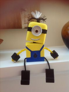 a yellow and blue minion toy sitting on top of a counter next to a vase