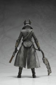 the action figure is dressed in silver and holding two large metal objects on his arm