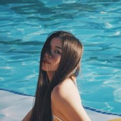 a woman in a bathing suit sitting next to a swimming pool