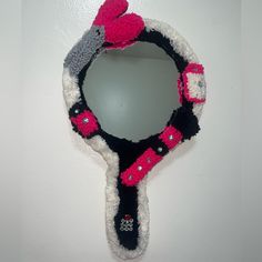 a mirror hanging on the side of a white wall with a pink and black scarf around it