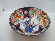 a decorative bowl is sitting on a white tablecloth with an orange and blue design