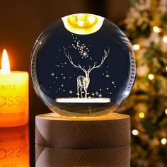 a glass ball with a deer on it next to a lit candle