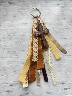 the key chain is made out of fabric and has a wooden cross on one end