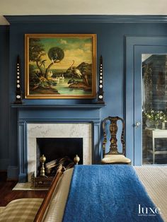 a bedroom with blue walls and a painting on the wall above the bed, along with a fireplace