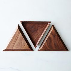 two triangle shaped wooden cutting boards sitting on top of each other