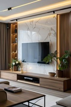 a living room with a large television on the wall and some plants in vases