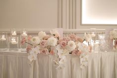 the table is set with candles, flowers and glass vases on it's side