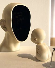 an alien head with a baby sitting next to it