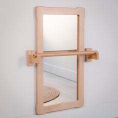 a mirror mounted to the side of a white wall next to a wooden floor mat