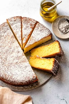 a cake on a plate with one slice cut out and the rest sliced off, sitting next to a cup of tea