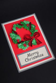 a christmas card with holly wreath and ribbon