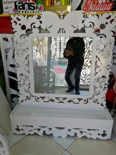 a man taking a photo in a mirror at a store with an ornate white frame