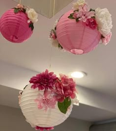 three pink and white paper lanterns hanging from the ceiling