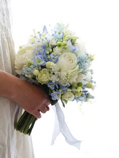 a woman holding a bouquet of white and blue flowers