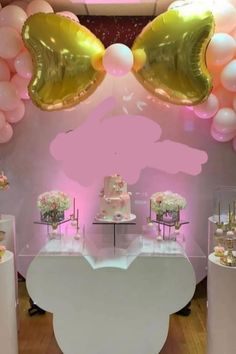 a table topped with lots of cake next to pink and white balloons in the air