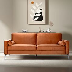 an orange couch sitting in front of a painting on the wall