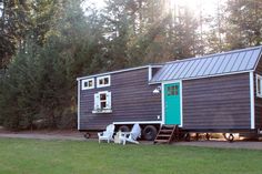 a tiny house is parked in front of some trees and has a ladder to the side