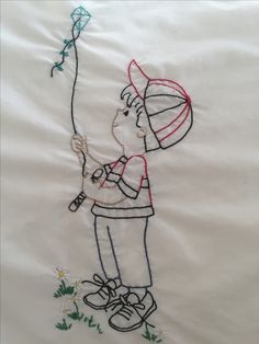 a drawing of a boy holding a kite on a white sheet with grass and flowers