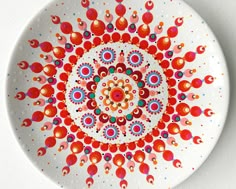 a white plate with red, blue and orange designs on the rim that has circles in it