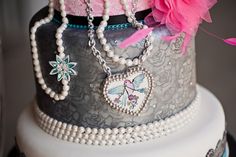 a close up of a cake with pearls and jewelry on it's tiers