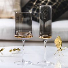 three wine glasses sitting on top of a white table next to a butterfly figurine