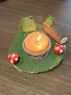 a lit candle sitting on top of a green plate next to mushrooms and a tree branch