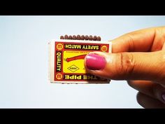 a woman's hand holding an unopened matchbox with pink nail polish