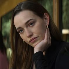 a close up of a person sitting down with her hand on her chin and looking at the camera