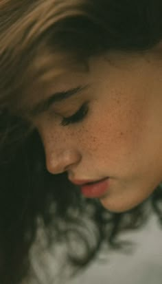 a woman with freckled hair is looking down at her cell phone