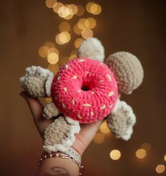 a hand holding a crocheted doughnut with sprinkles on it