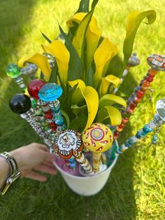 a vase filled with yellow flowers and lots of colorful glass bead decorations on top of green grass